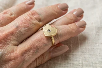 Gros plan sur une bague cœur magnétique en or brossé portée au doigt, mettant en valeur les détails de fabrication et le mécanisme de fermeture magnétique