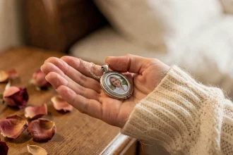 Femme tenant un médaillon argenté ouvert avec une photo projetée à l'intérieur, posé dans sa paume, ambiance romantique et intime