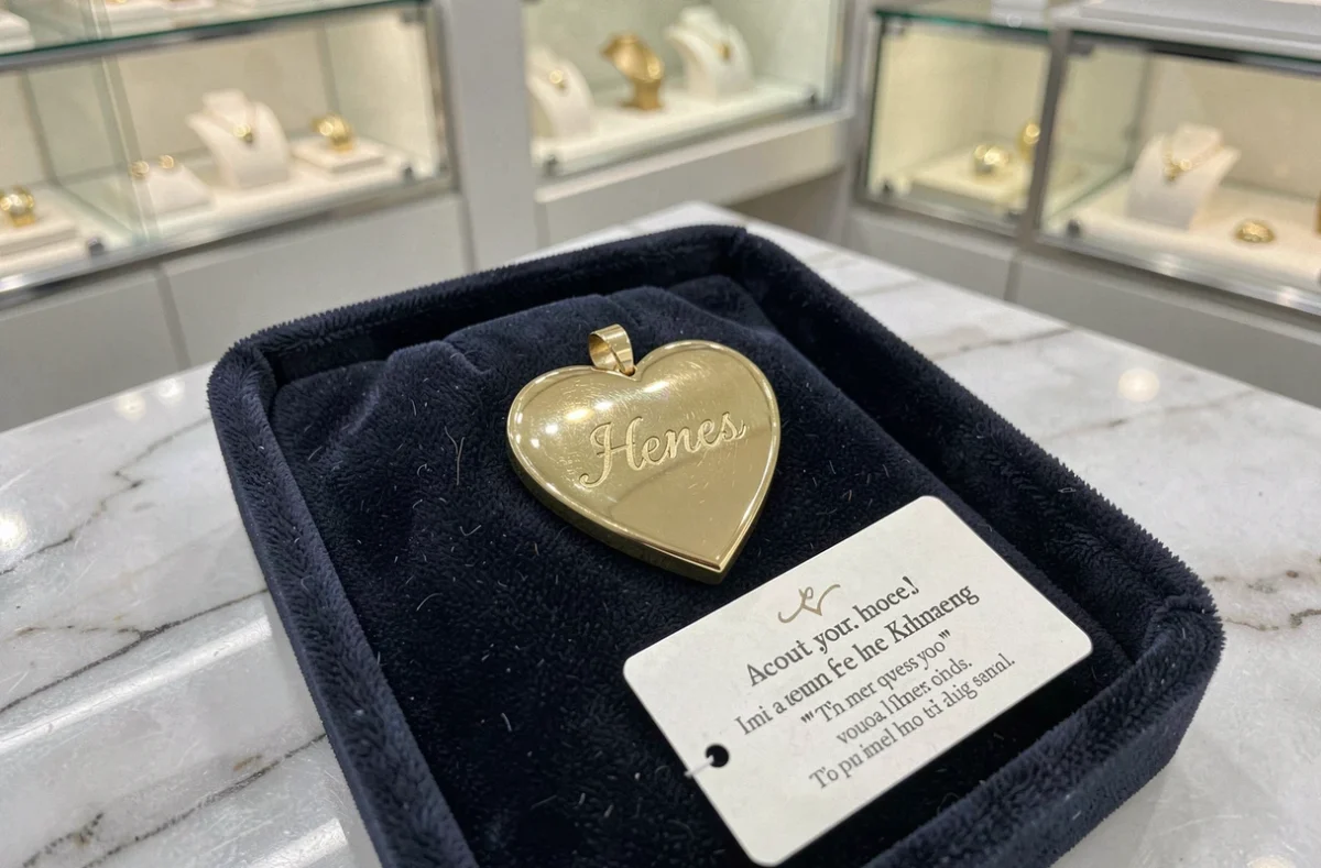 Pendentif en or gravé avec initiales posé sur velours dans une bijouterie de luxe